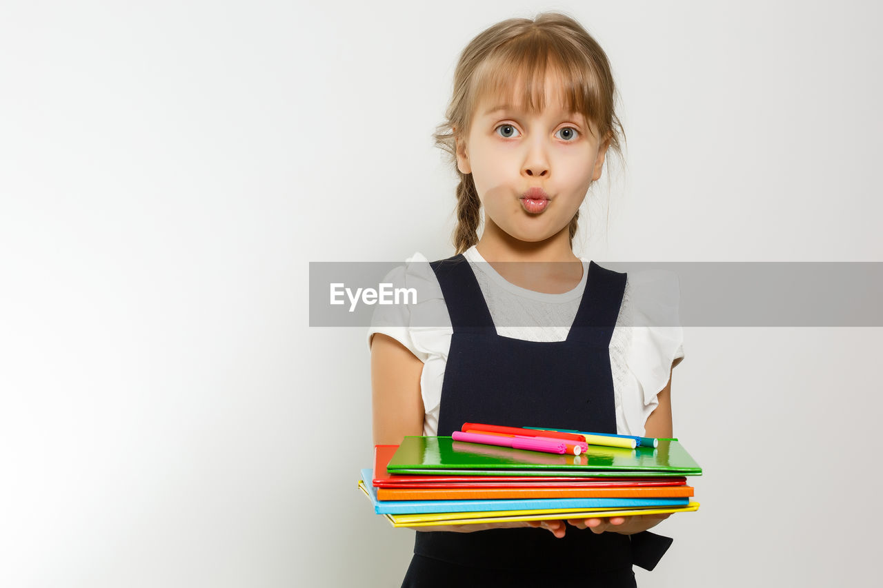 PORTRAIT OF GIRL IN BOOK AGAINST WHITE BACKGROUND