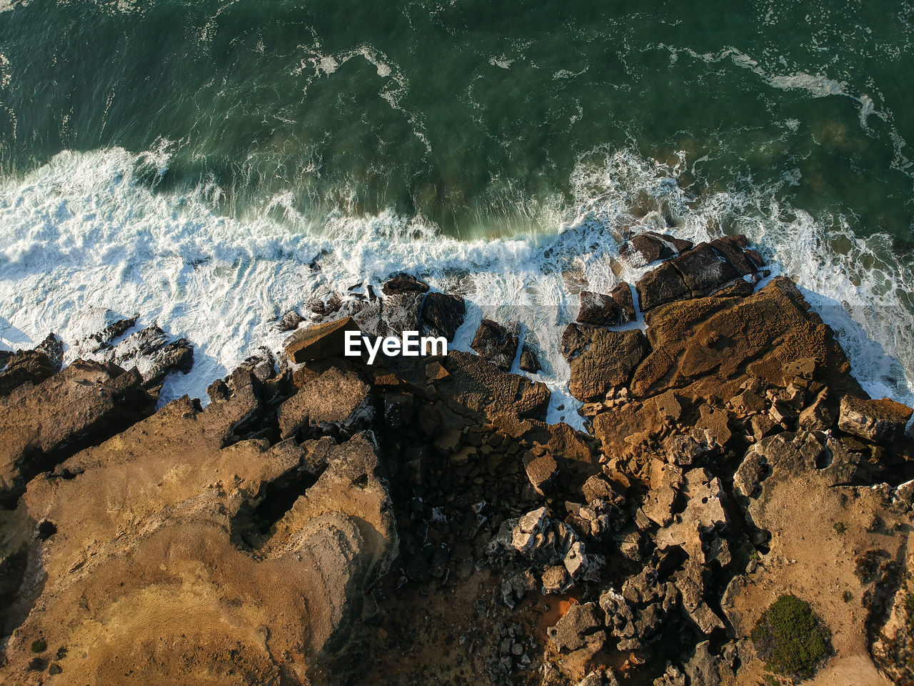 Aerial view of sea waves splashing on rocks