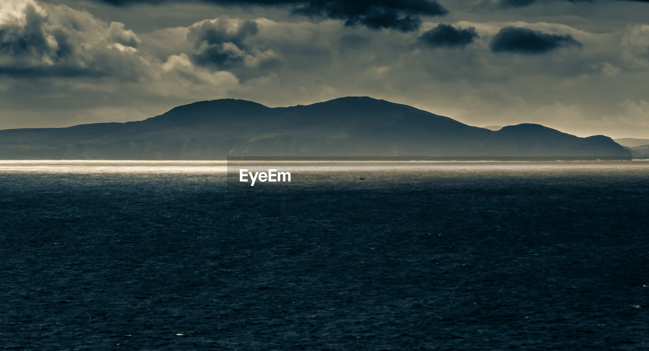 Scenic view of sea and mountains against sky