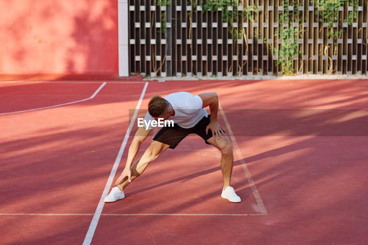 REAR VIEW OF MAN PLAYING WITH BALL IN SUNLIGHT