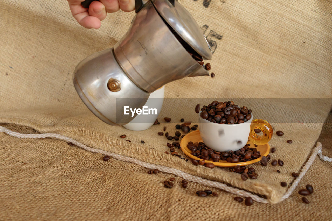 CLOSE-UP OF HAND HOLDING COFFEE CUP WITH CHOCOLATE