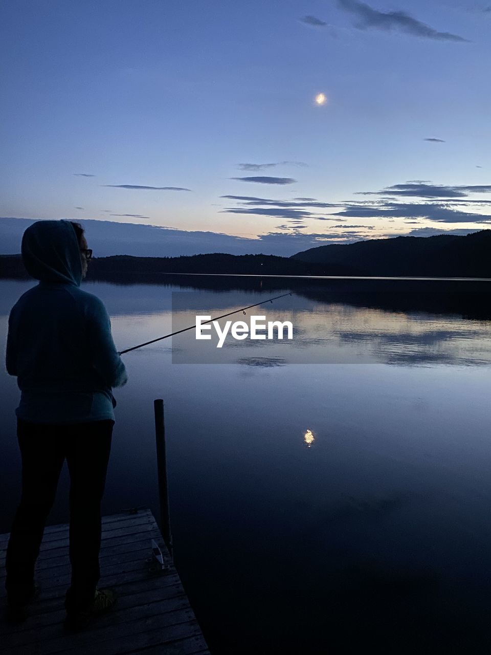 REAR VIEW OF MAN LOOKING AT LAKE AGAINST SKY