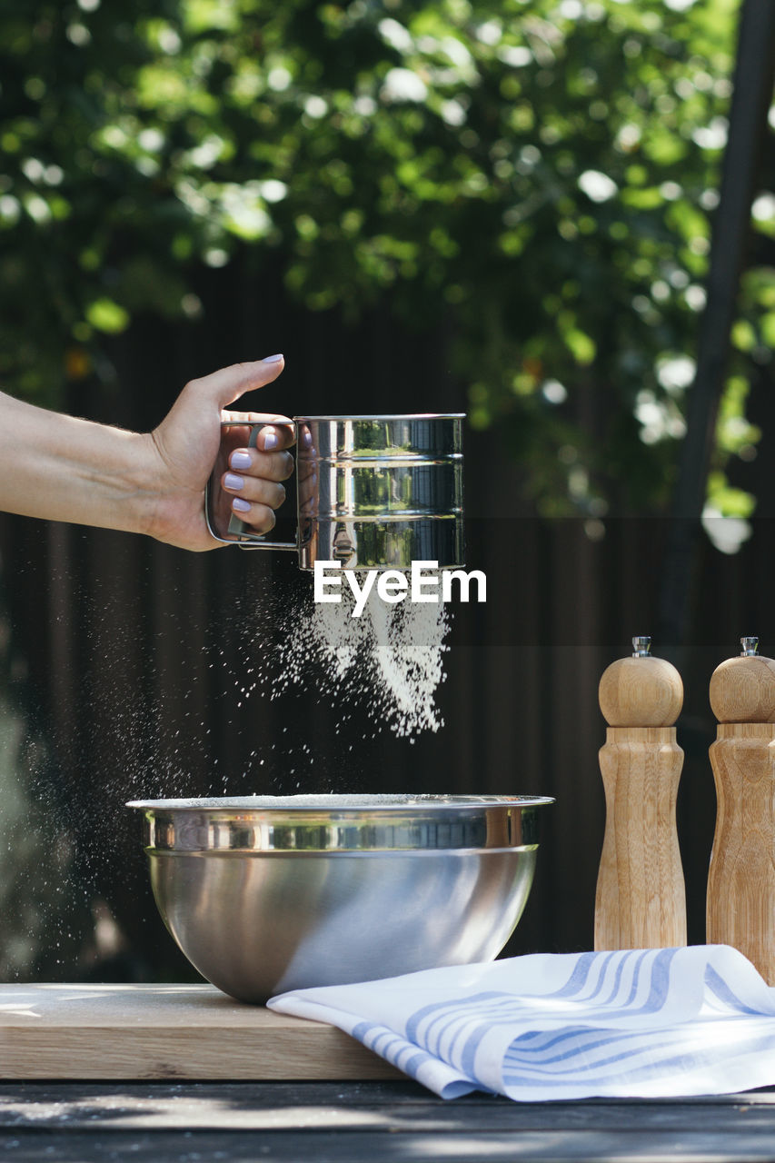 A woman's hand sifting flour for baking