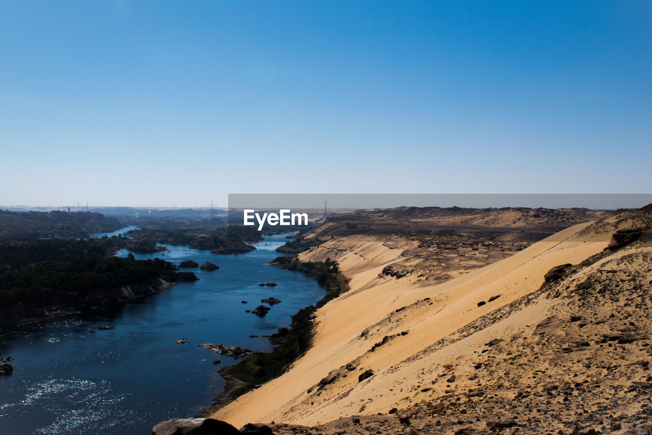 Scenic view of river valley against sand dunes with clear sky