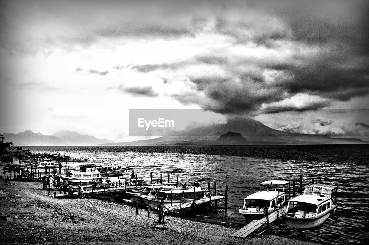 Boats moored on harbor against sky