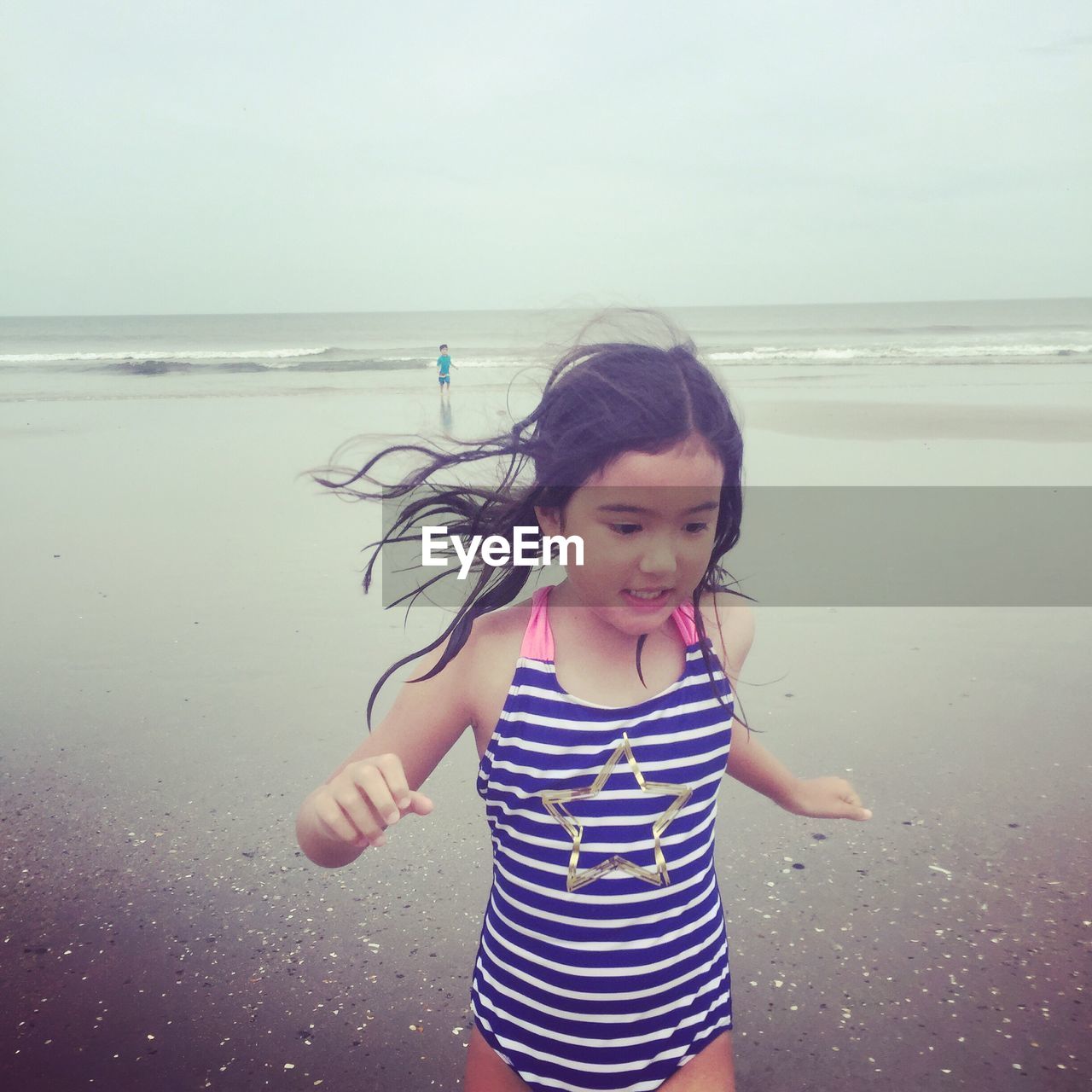 Cute girl walking at beach against sky