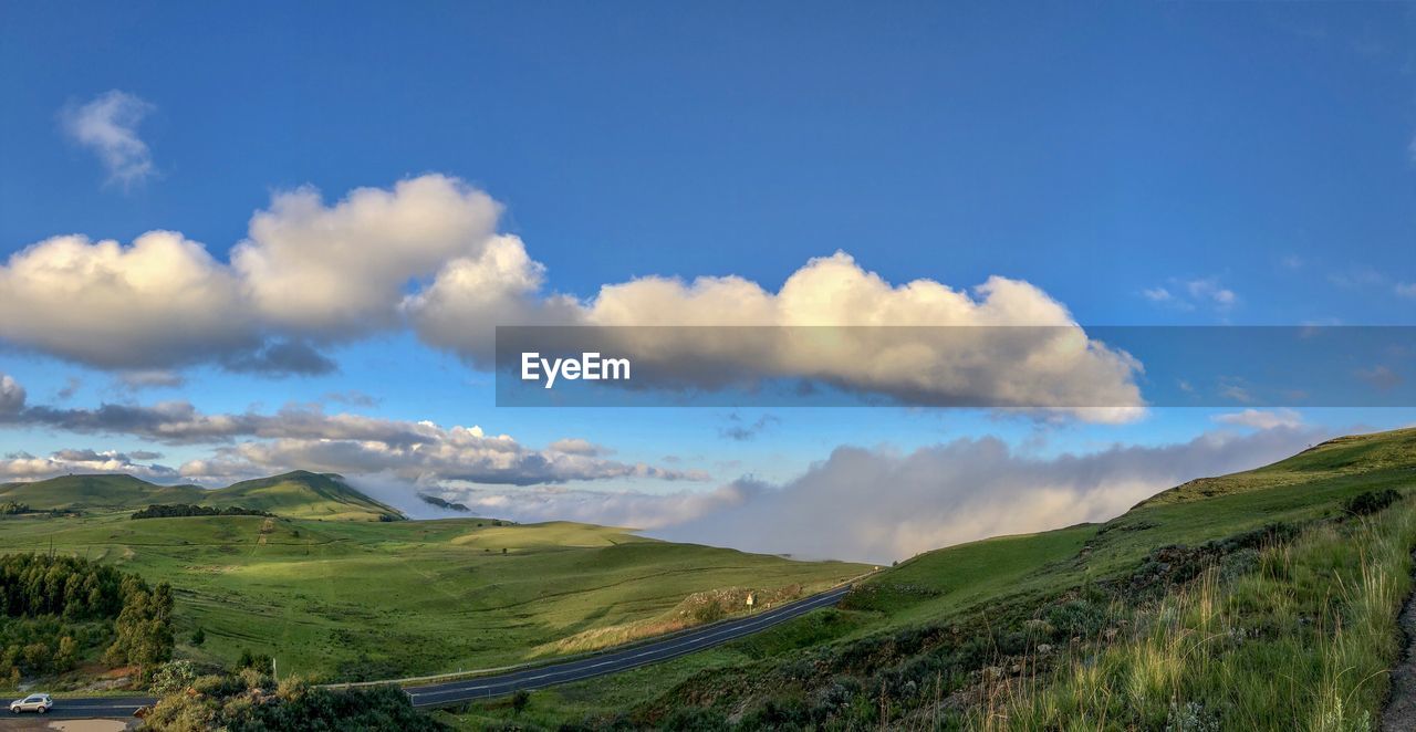 Panoramic view of road amidst field against sky