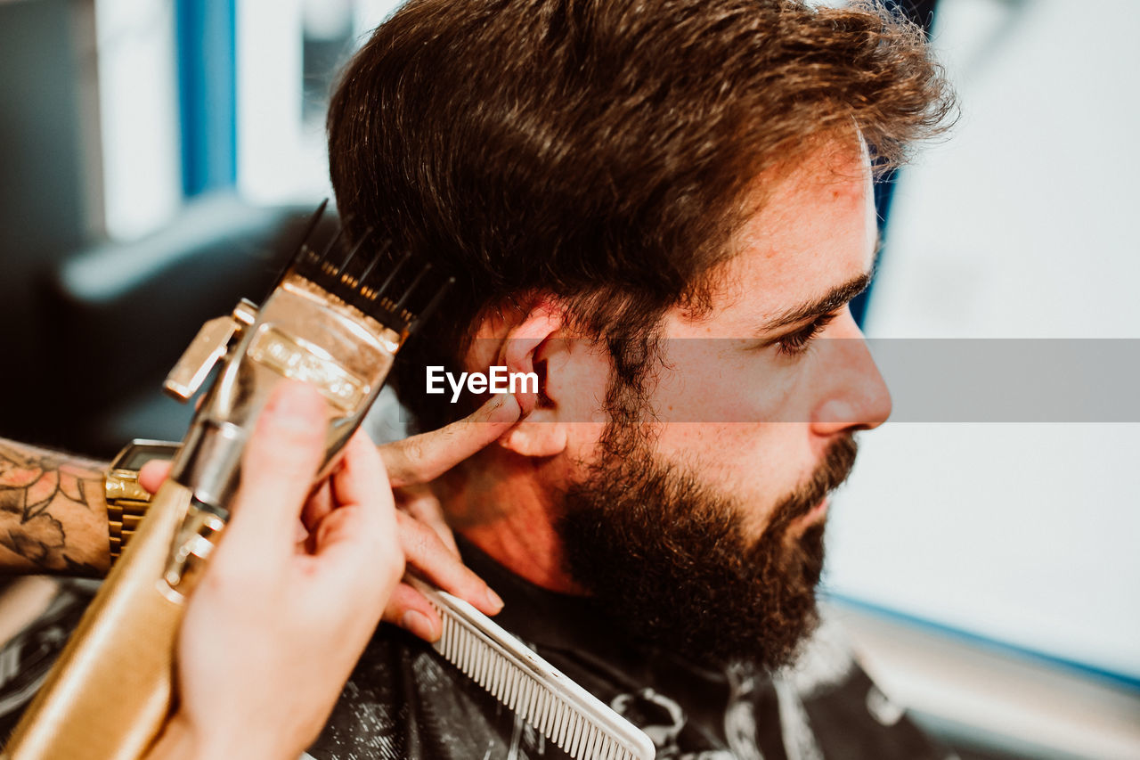 Cropped hands of barber grooming customer in salon