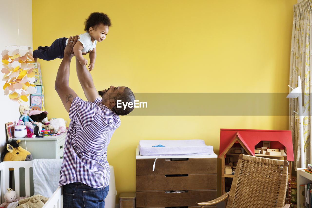 Happy man picking up son while standing at home