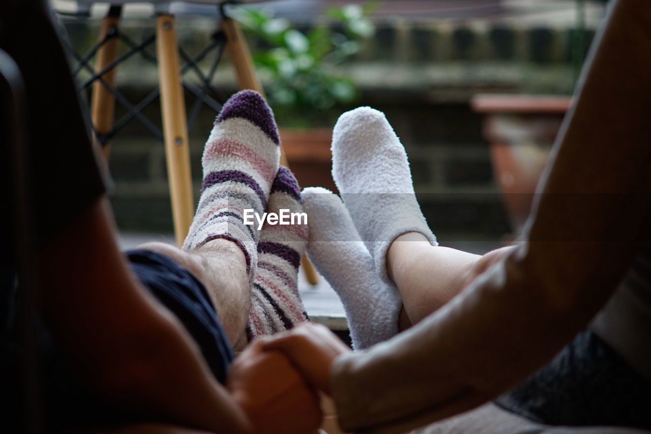 Low section of couple holding hands while sitting at patio