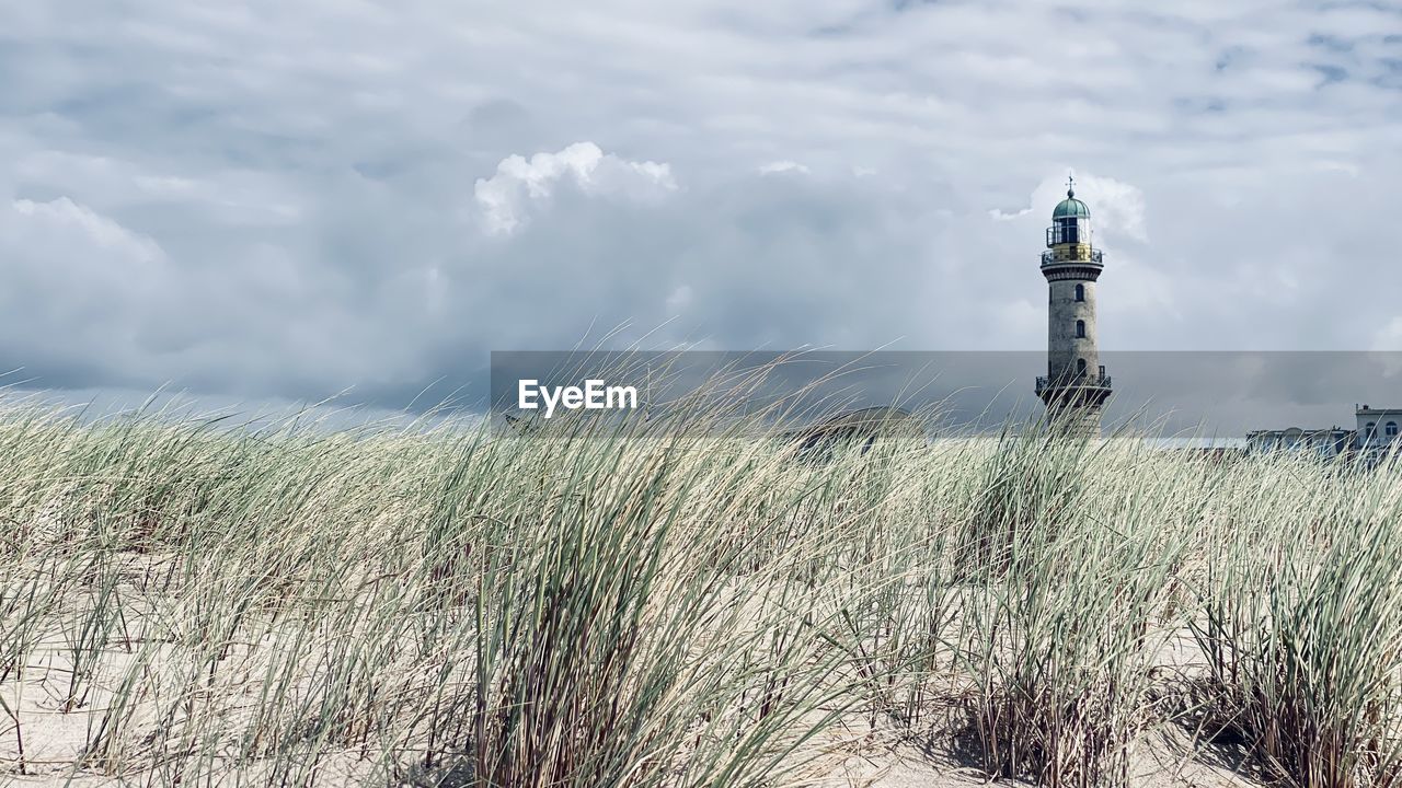 lighthouse, sky, cloud, guidance, nature, tower, plant, architecture, grass, built structure, land, prairie, landscape, security, protection, wind, environment, building exterior, sea, no people, day, building, outdoors, scenics - nature, travel destinations, coast, travel, beach, field, beauty in nature, non-urban scene, tranquility, horizon, sand dune