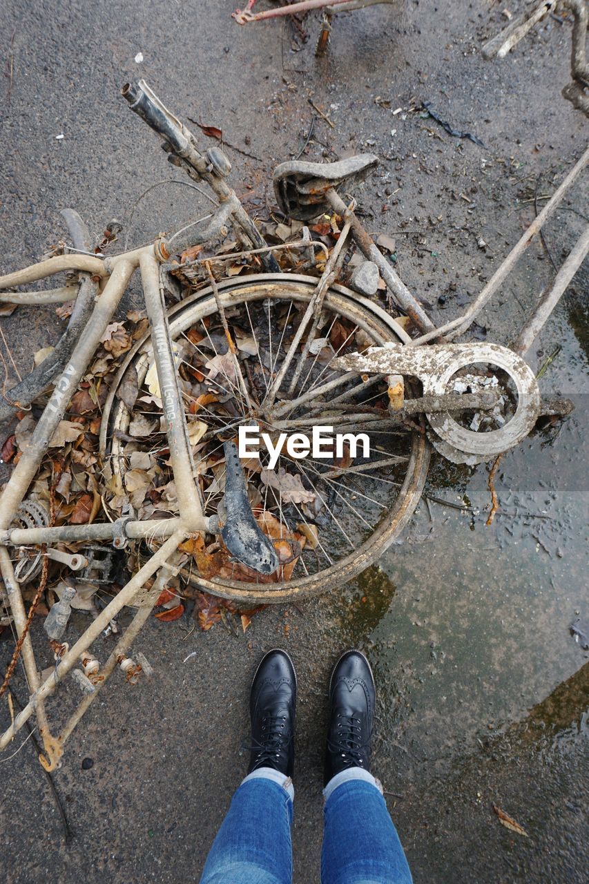 LOW SECTION OF PERSON STANDING BY BICYCLE ON ROAD