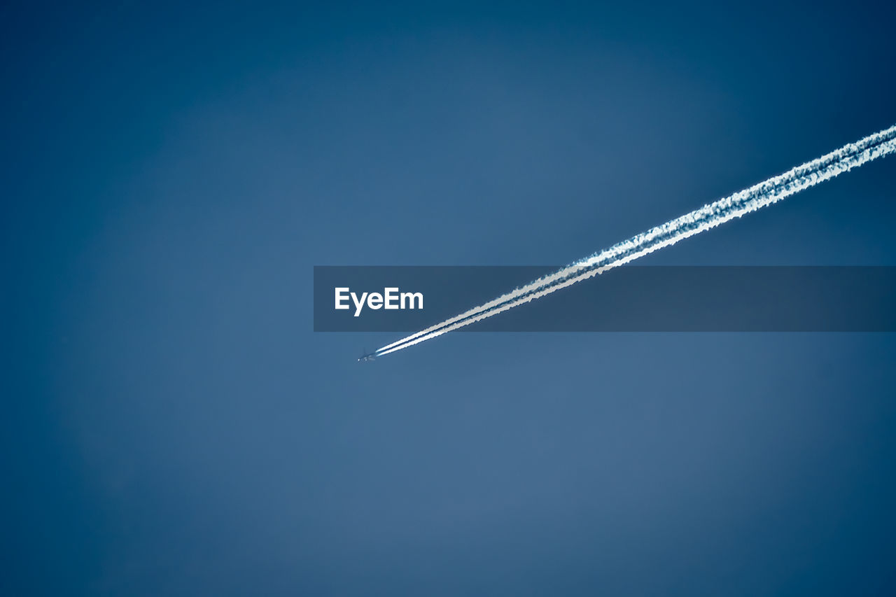 Low angle view of vapor trail against clear blue sky