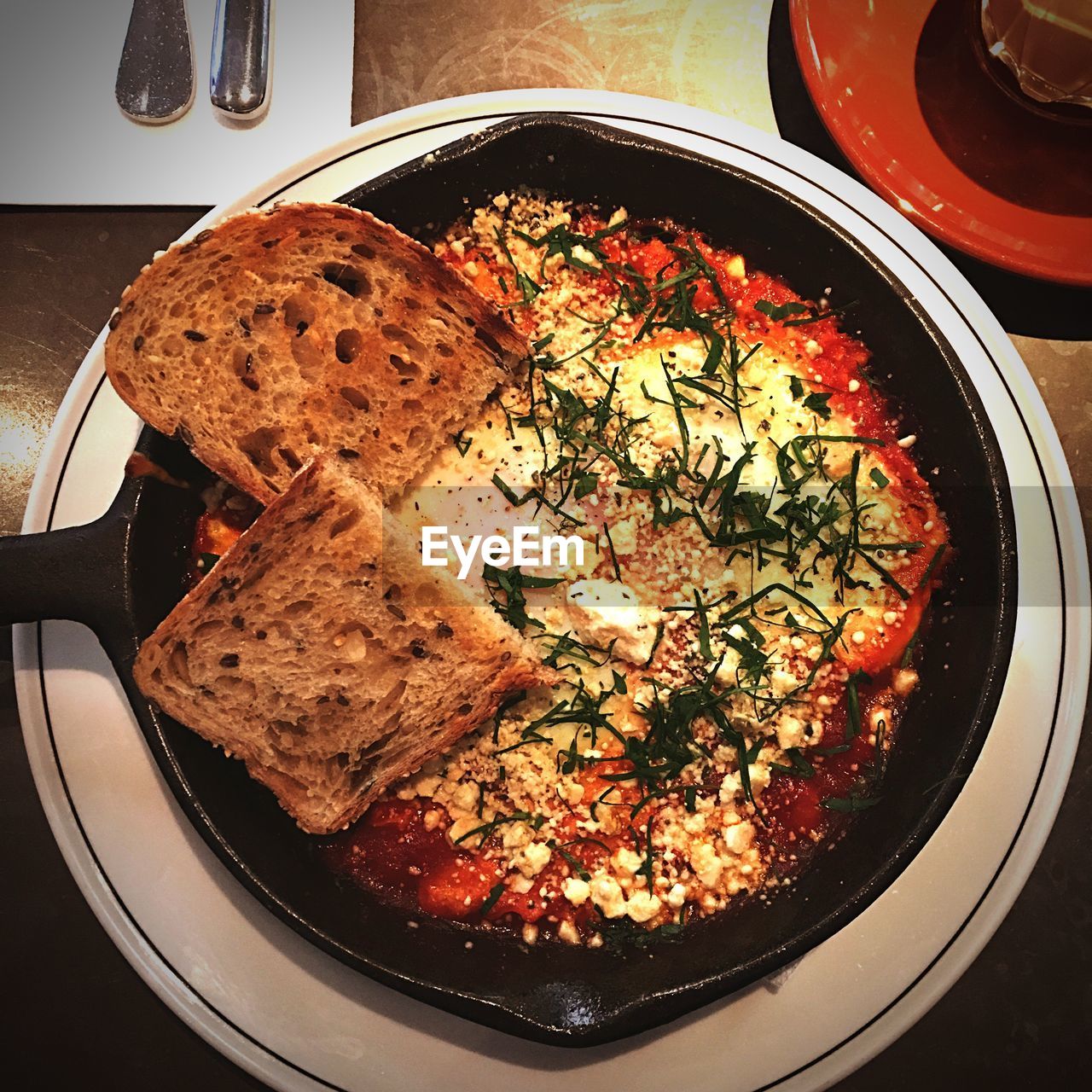 High angle view of shakshouka with breads in plate on table