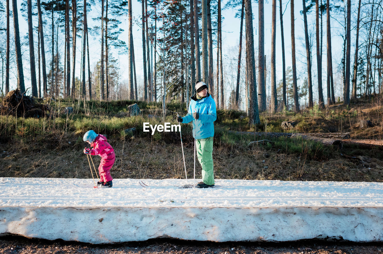 Father cross country skiing with his daughter in sweden at sunset