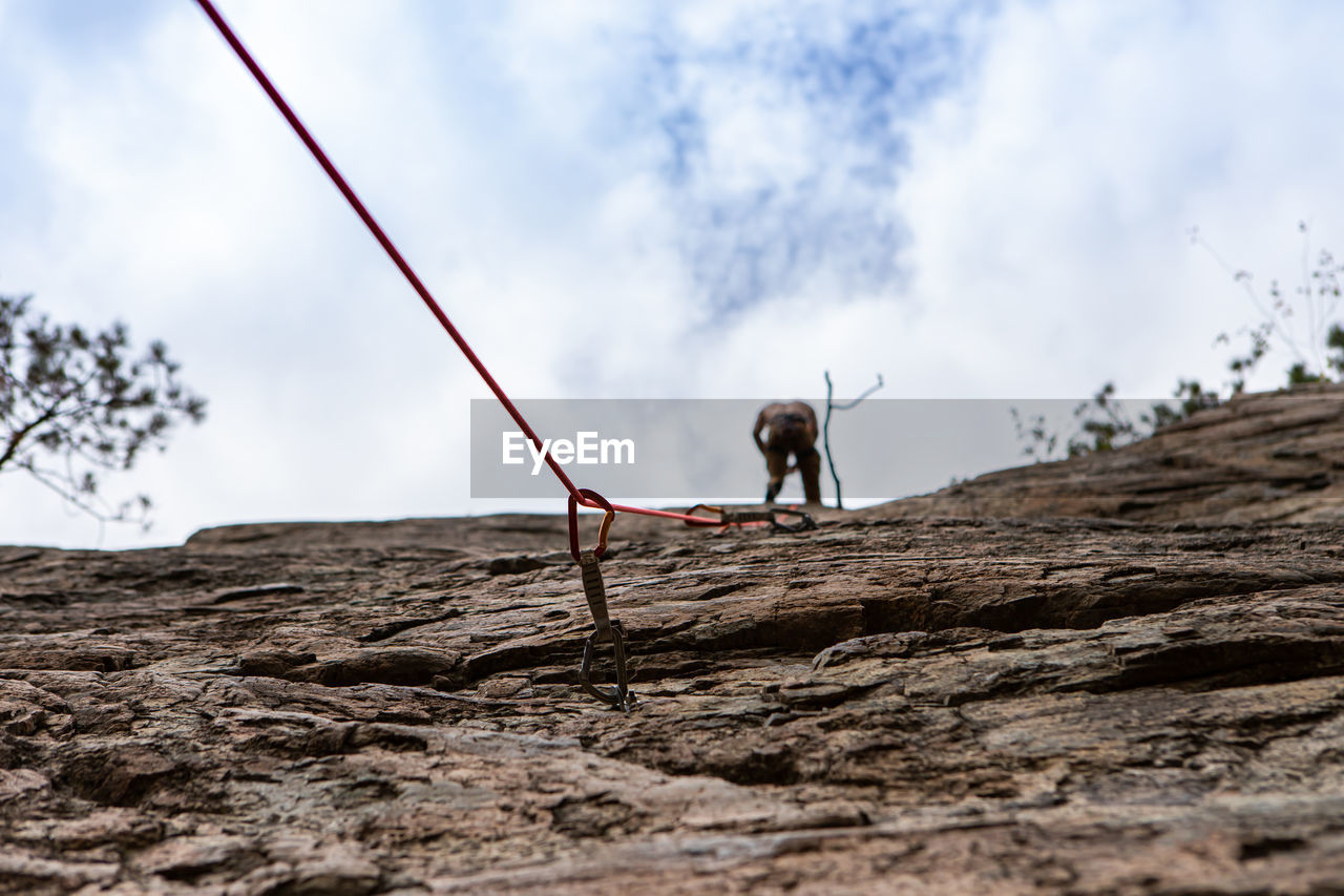 LOW ANGLE VIEW OF MAN CLIMBING ON LAND
