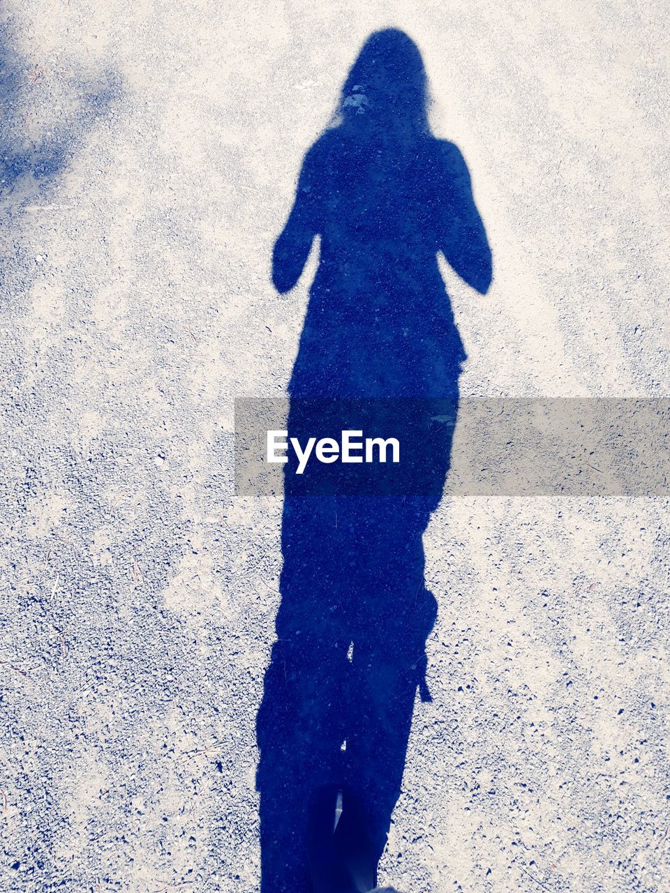 HIGH ANGLE VIEW OF PERSON SHADOW ON STREET IN SNOW