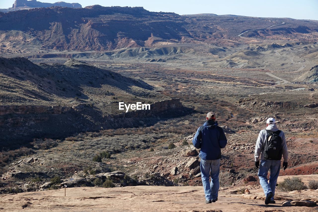 Rear view of men walking on mountain at arches national park