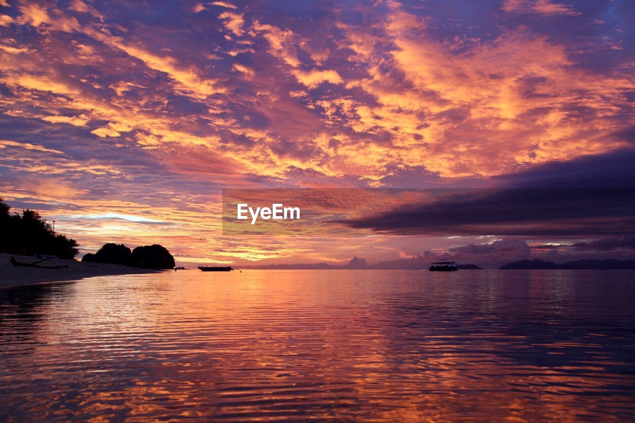 Scenic view of sea against dramatic sky during sunset