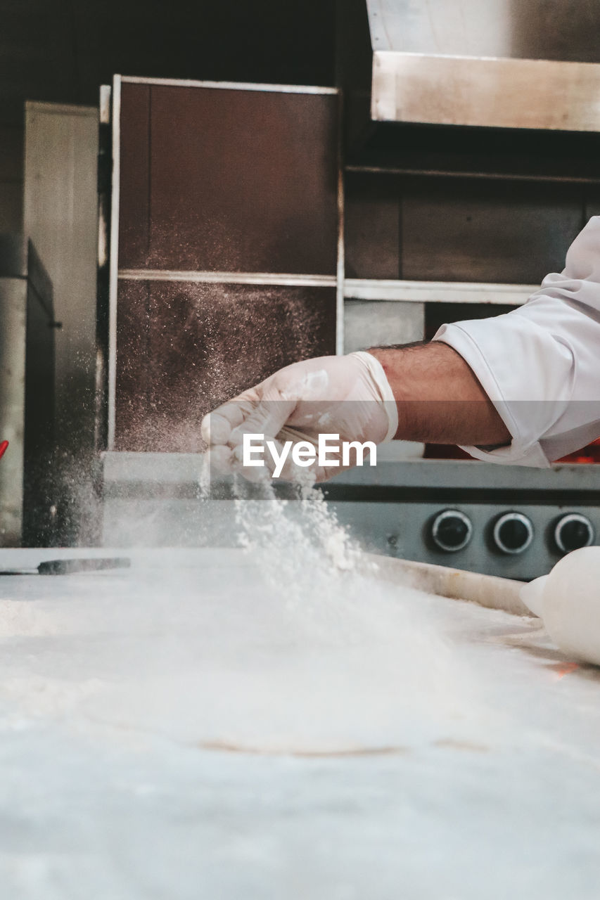 Cropped hand of chef preparing food in commercial kitchen