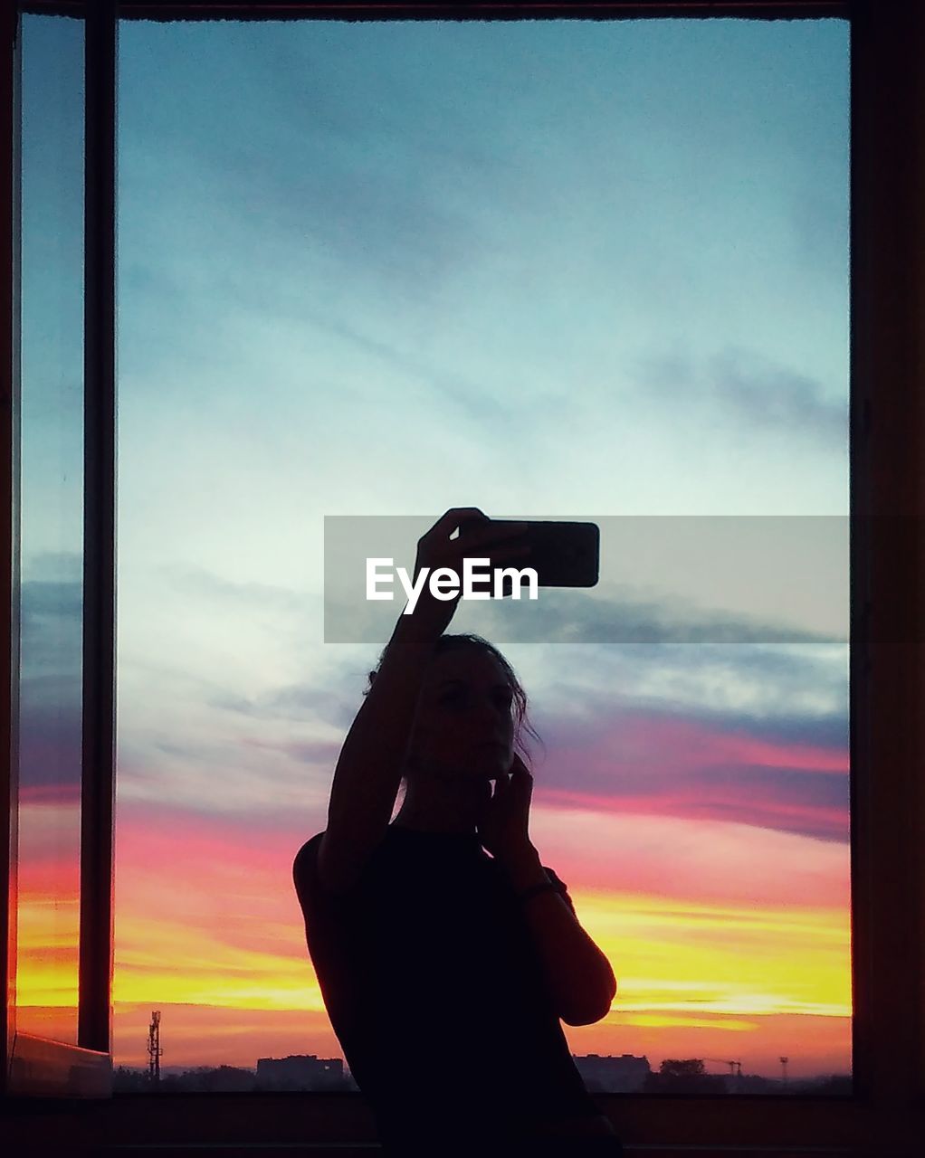 Silhouette woman taking selfie against sky during sunset