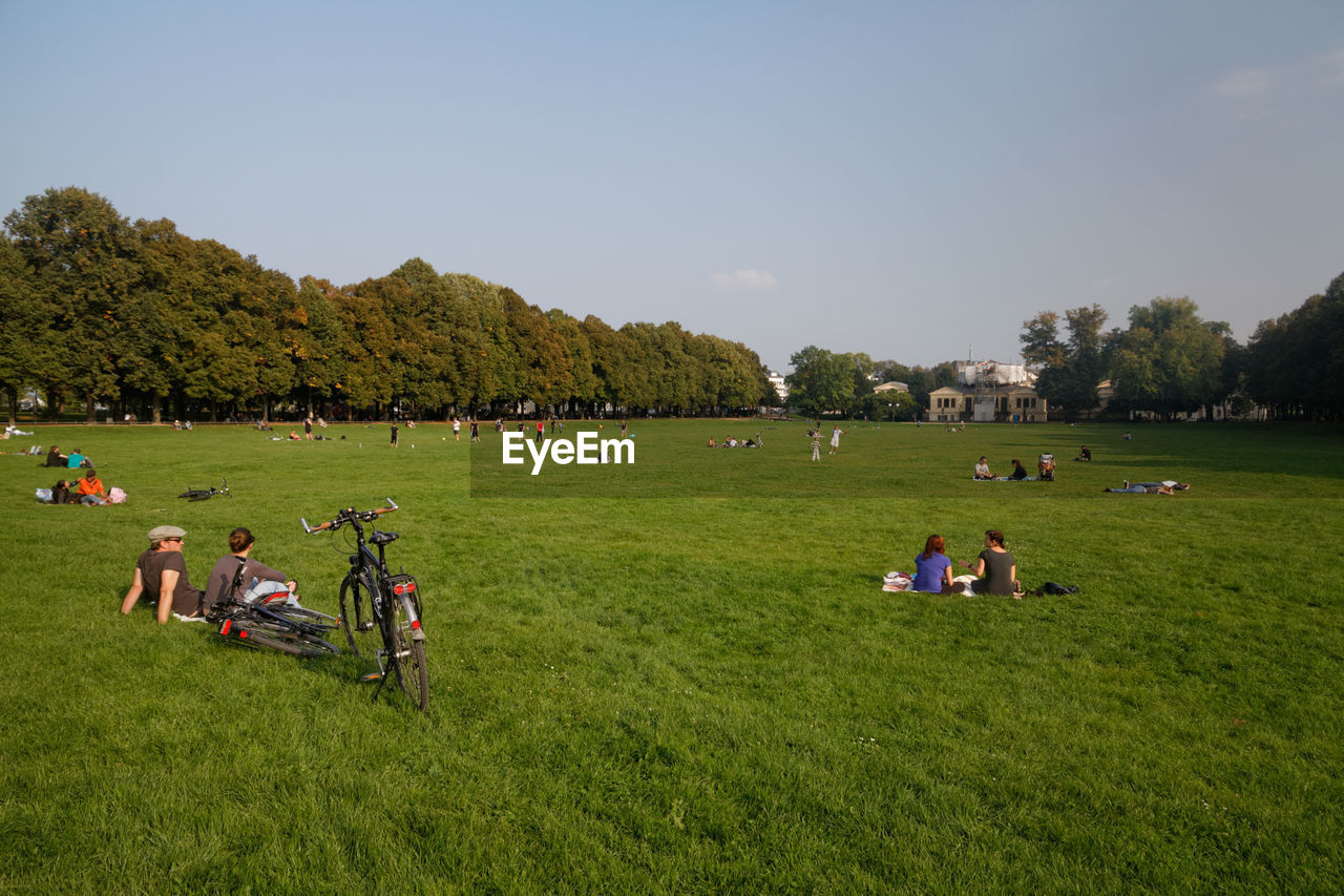PEOPLE SITTING ON GRASSY FIELD