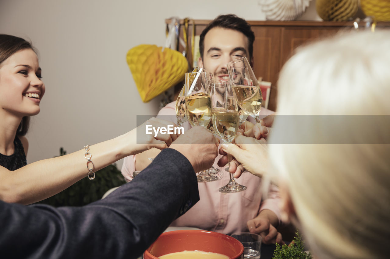 Laughing friends clinking glasses with champagne at new year's eve