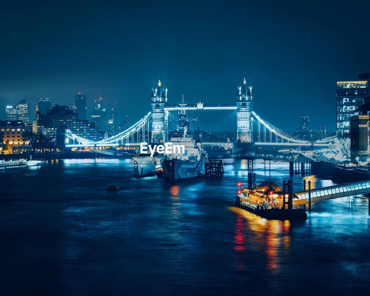 BRIDGE OVER RIVER IN CITY AT NIGHT