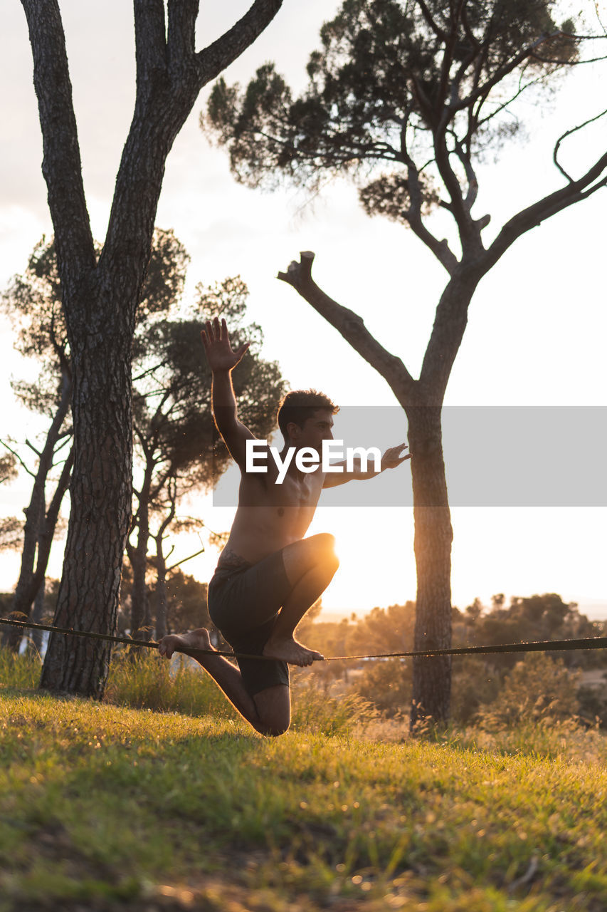 Man slacklining on tightrope during sunset