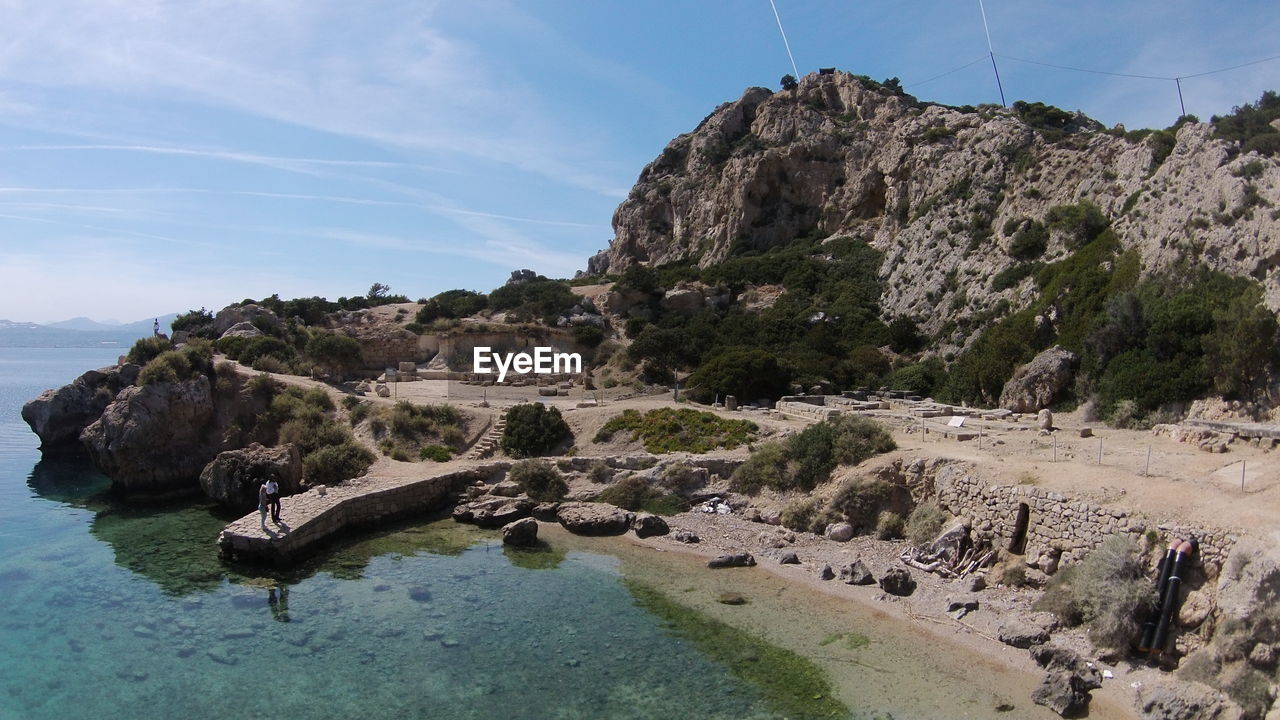 Scenic view of rock formation by sea against sky during sunny day