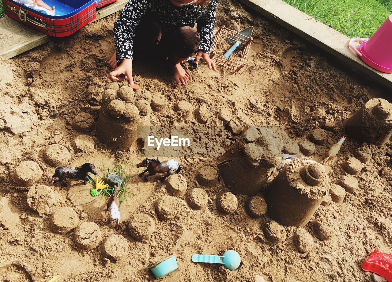 LOW SECTION OF CHILDREN PLAYING ON SAND