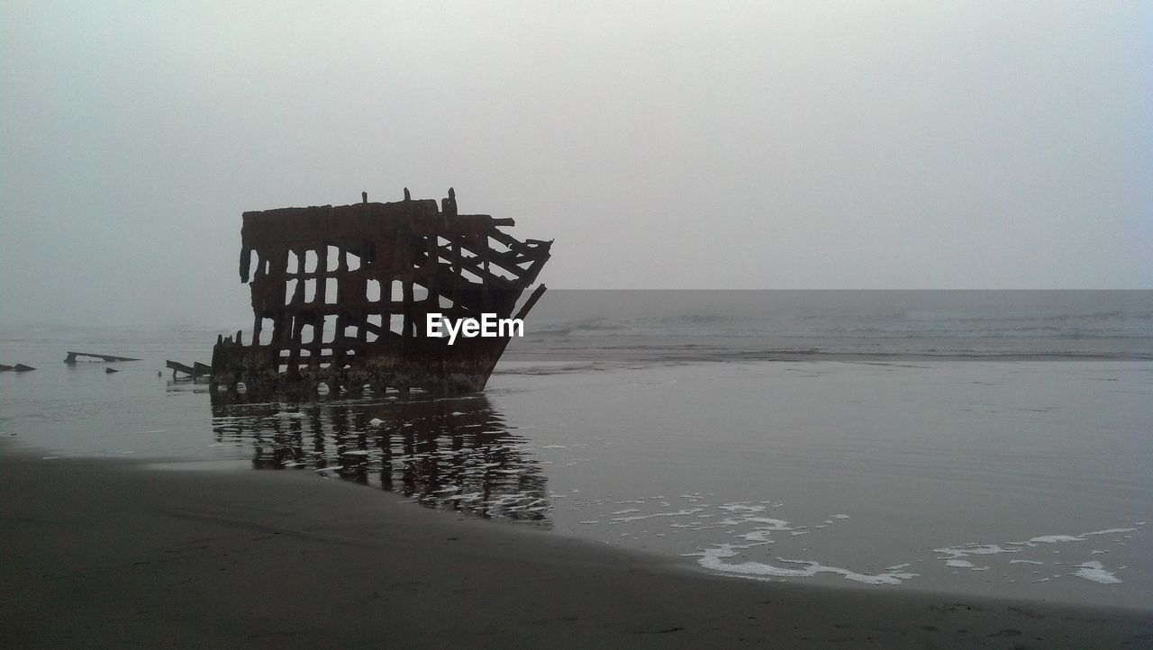 Silhouette built structure on beach against sky