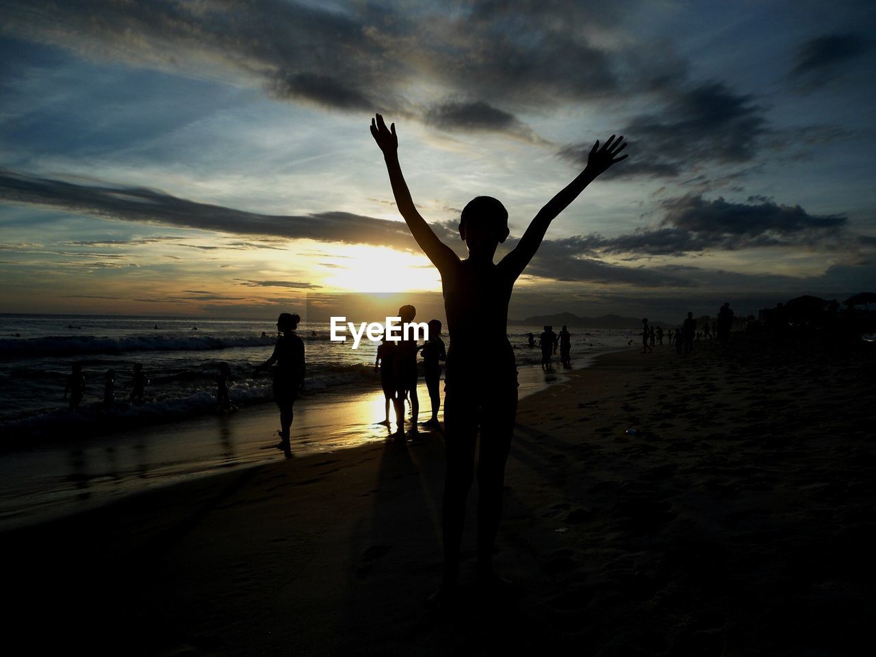 People relaxing on beach at sunset