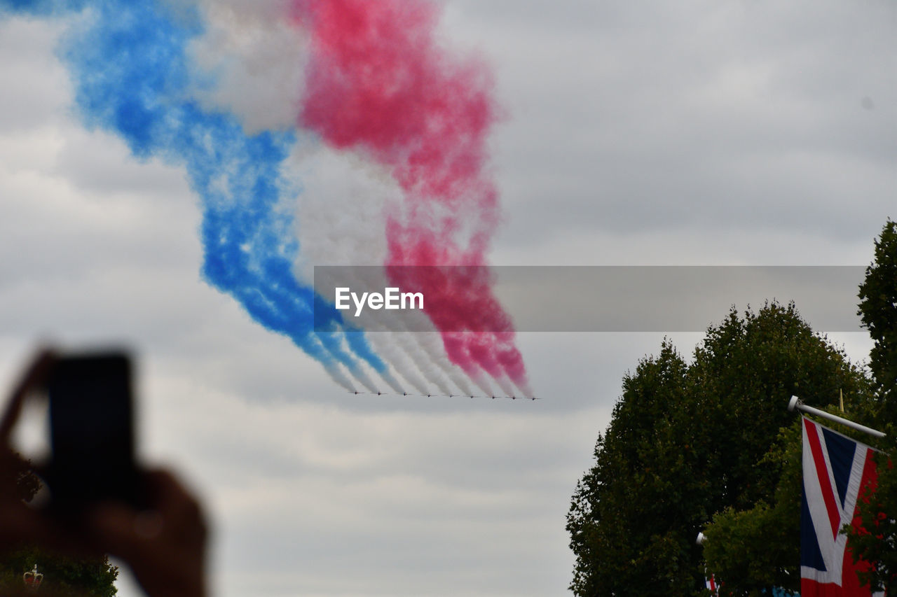 Human hand photographing airshow with mobile phone against sky