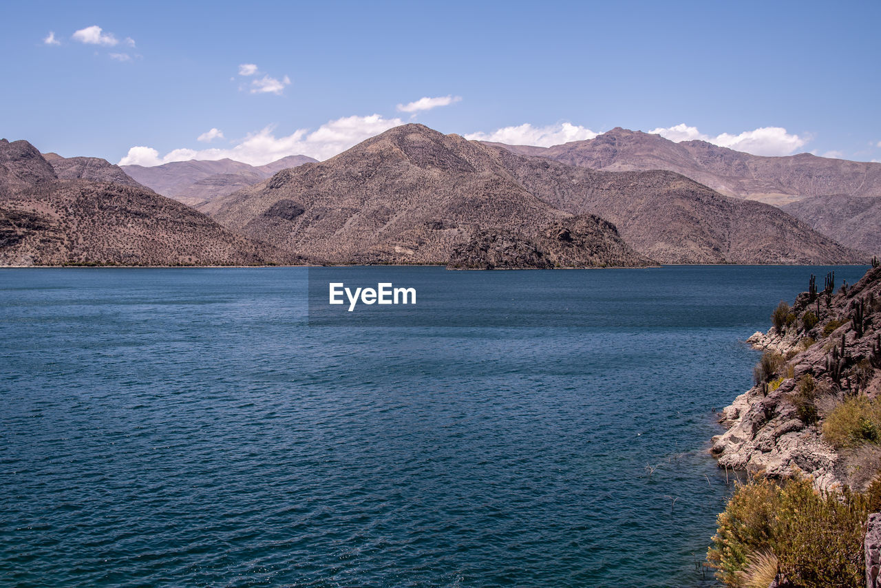 Scenic view of sea and mountains against blue sky