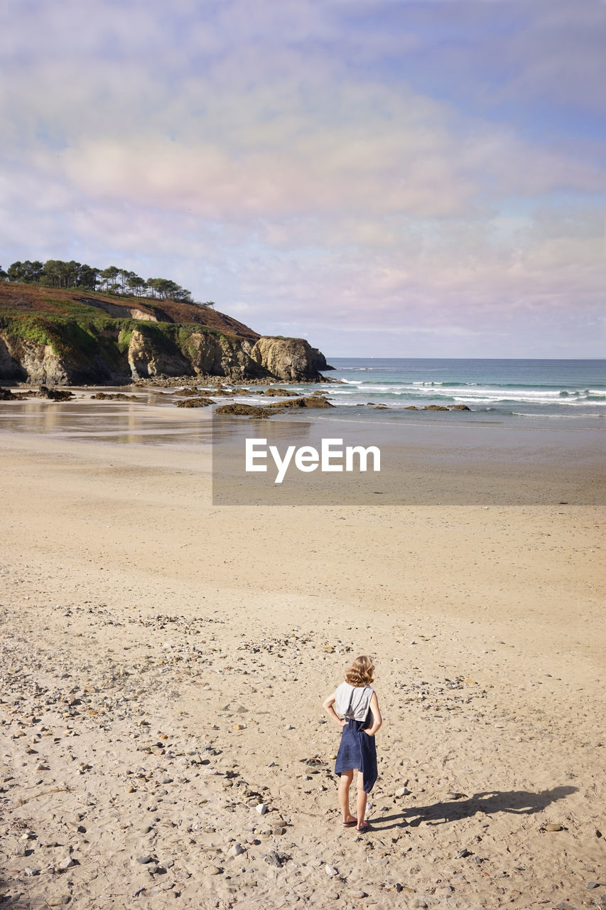 Rear view of woman standing on sand at beach