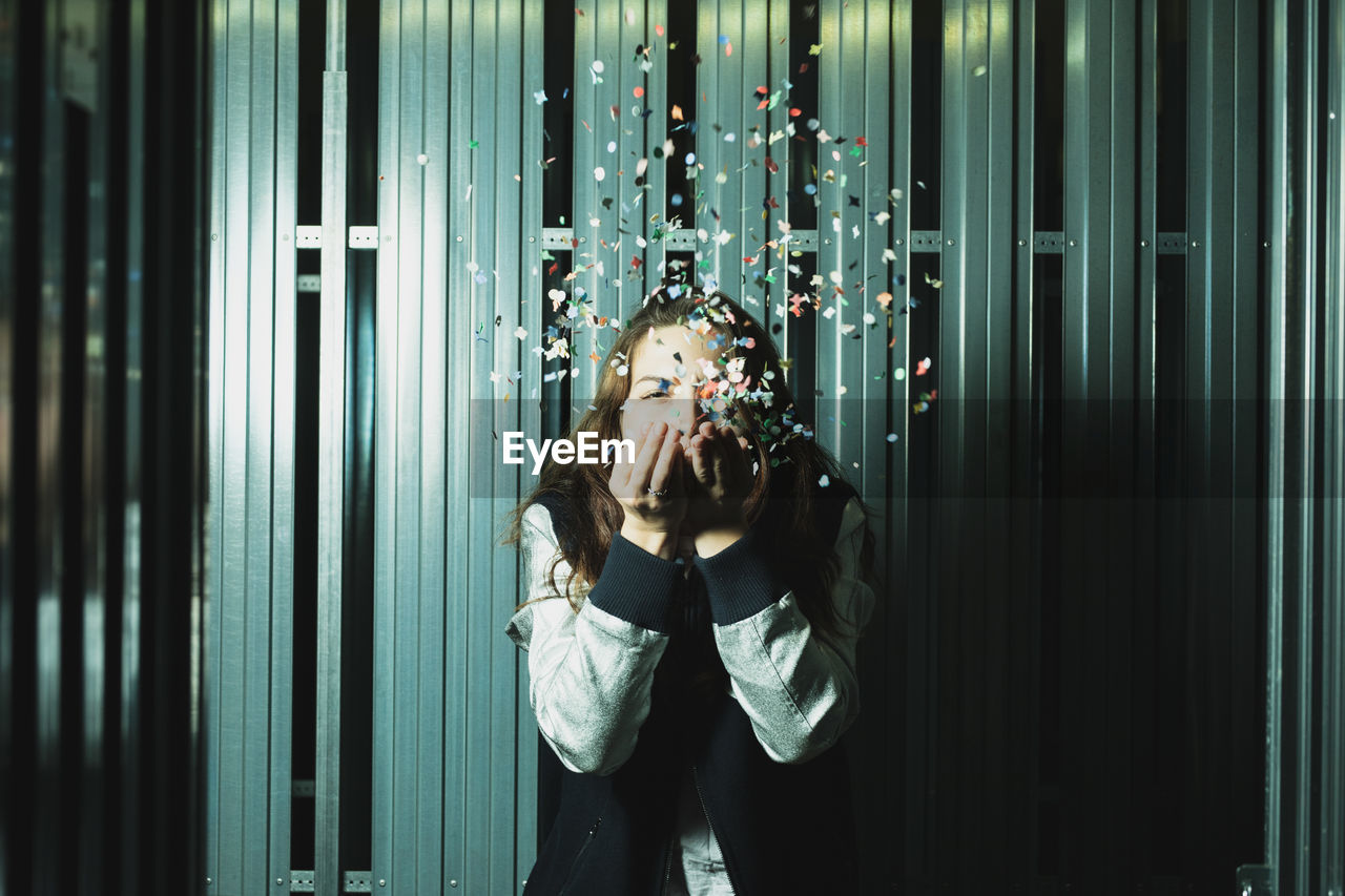 Woman blowing confetti against wall