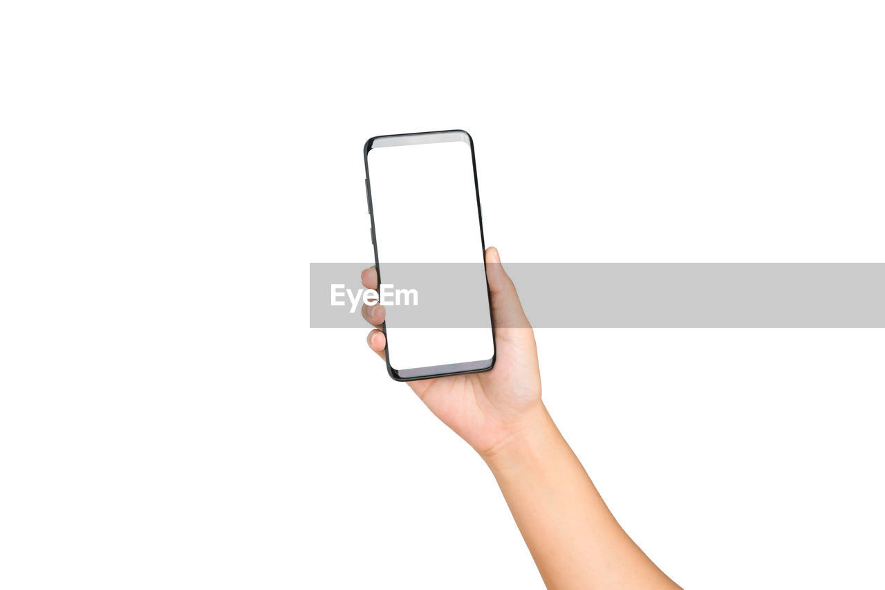 Cropped hand of woman holding mobile phone against white background