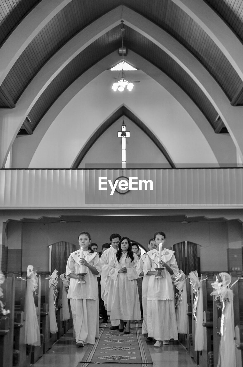 REAR VIEW OF PEOPLE STANDING AGAINST THE CEILING OF A CHURCH