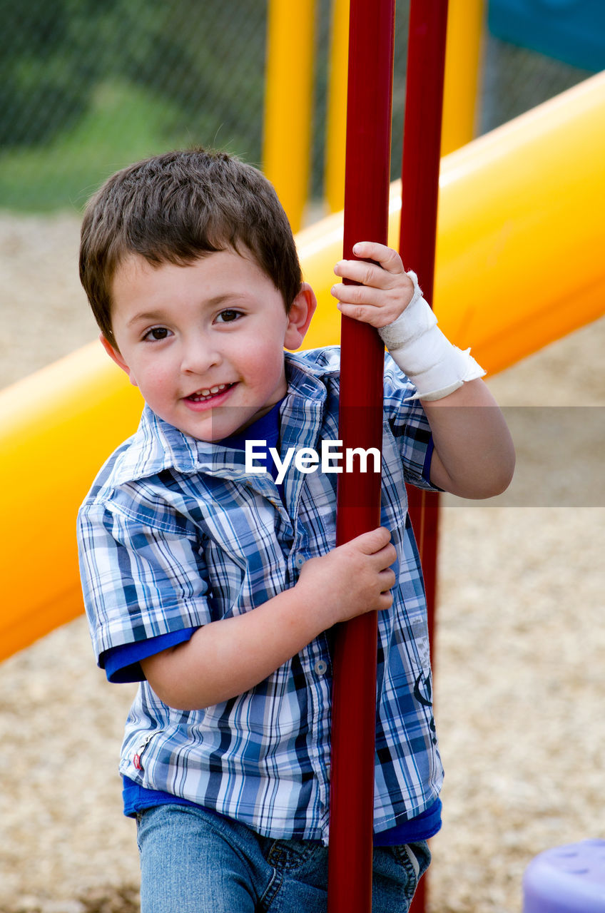 Young boy with a bandaged hand on a colorful playground