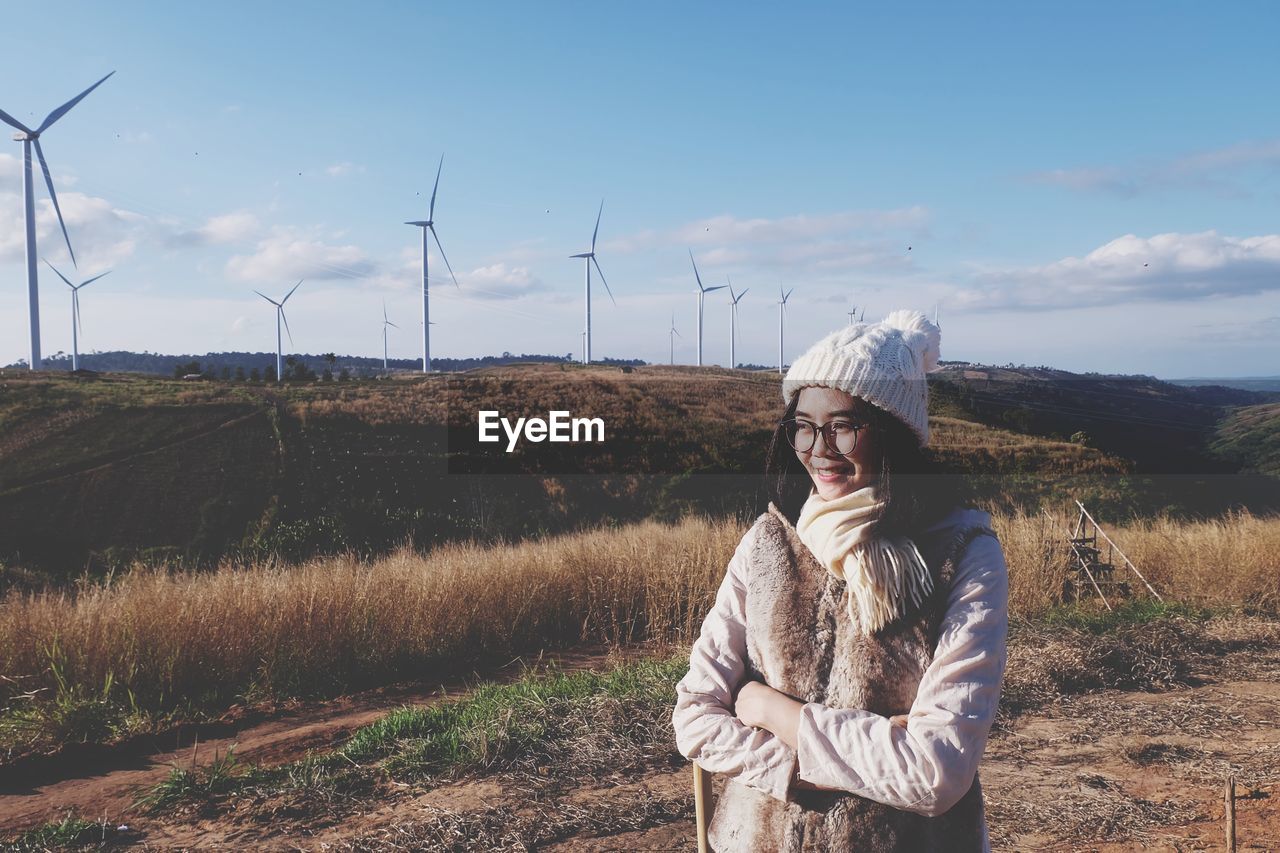 Woman wearing warm clothing while standing against windmills on mountain