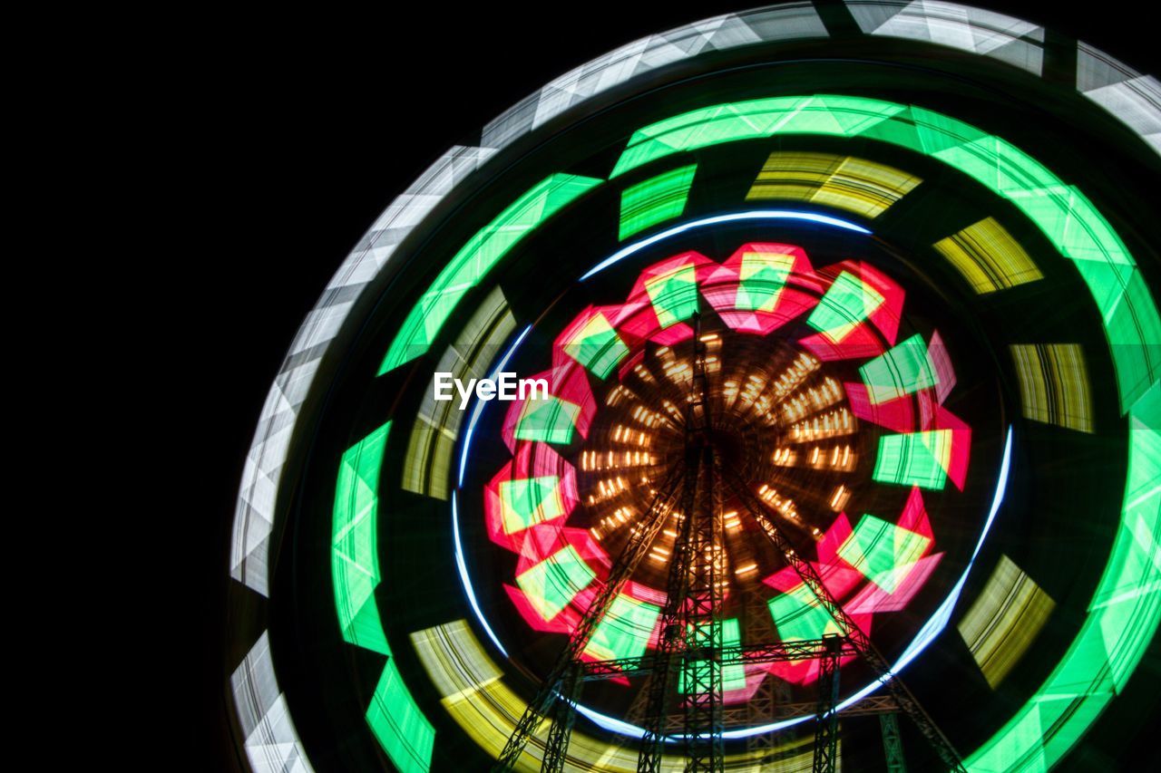 LOW ANGLE VIEW OF ILLUMINATED FERRIS WHEEL AGAINST BLACK SKY