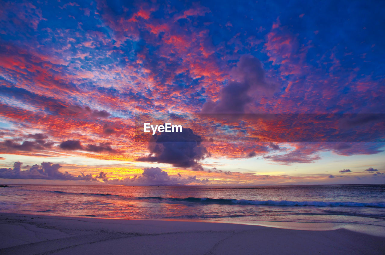 Scenic view of sea against dramatic sky during sunset