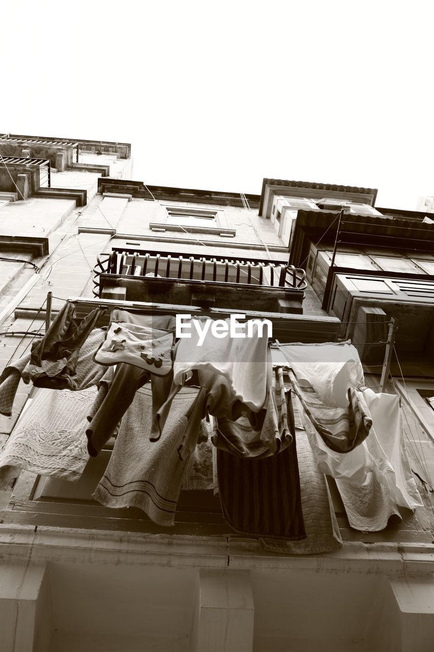 LOW ANGLE VIEW OF CLOTHES DRYING HANGING ON CLOTHESLINE