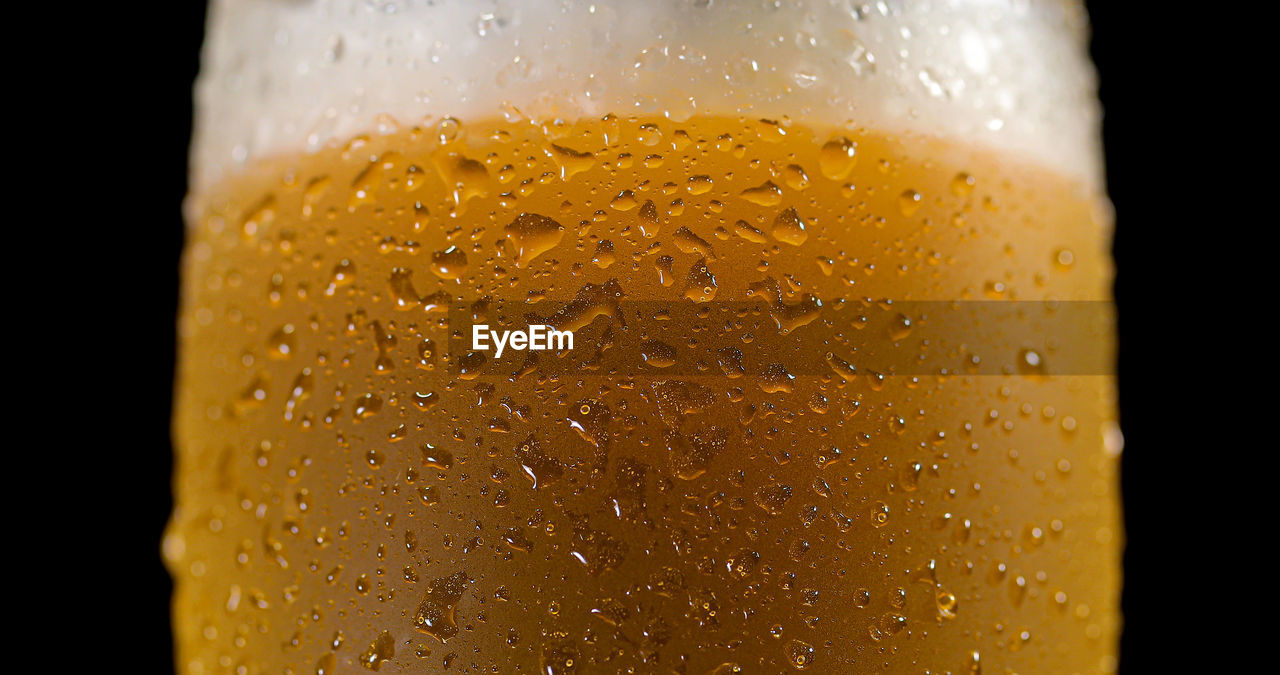 CLOSE-UP OF GLASS OF WATER DROPS ON BLACK BACKGROUND