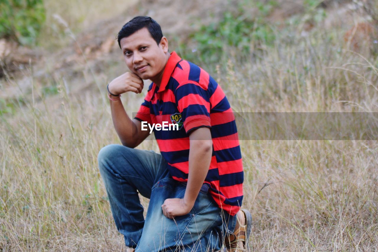 PORTRAIT OF HANDSOME YOUNG MAN SITTING ON LAND