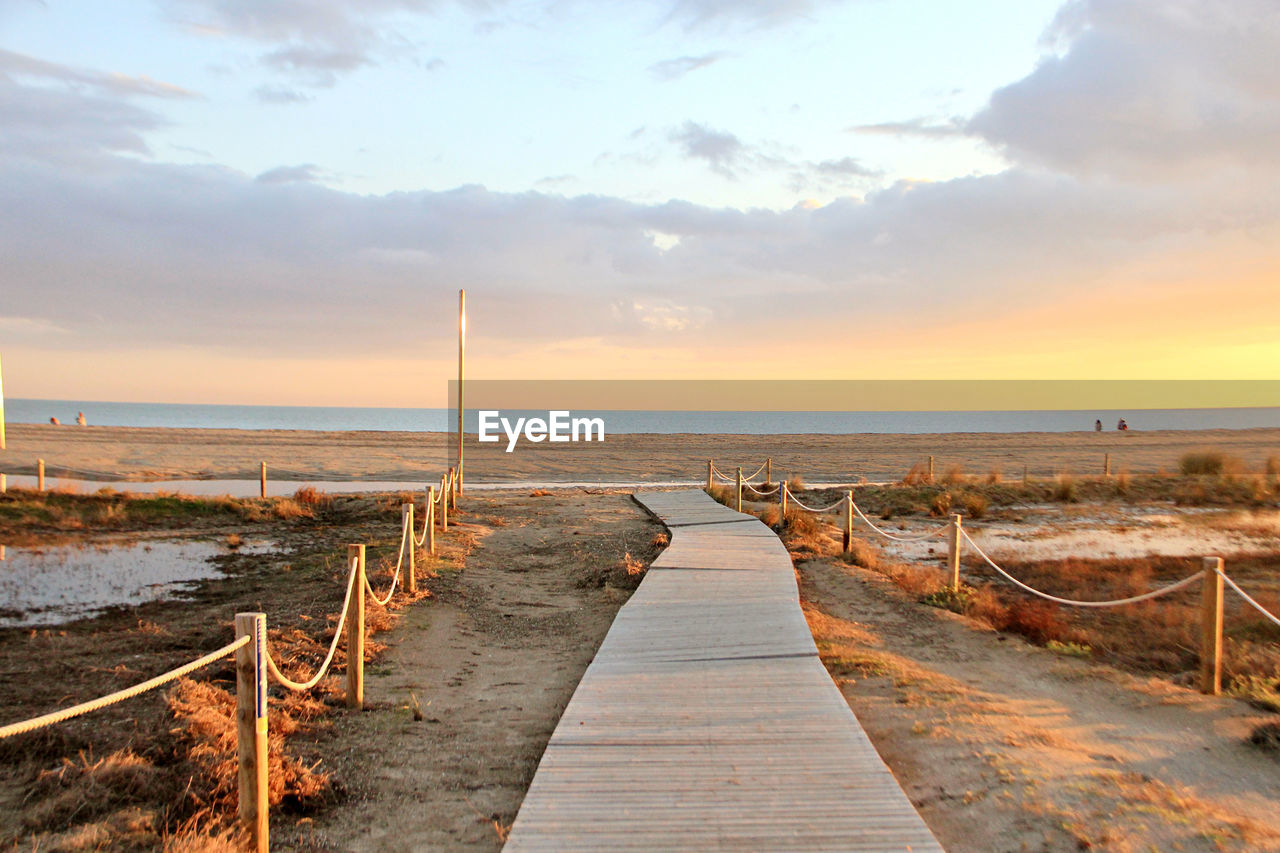 Wooden pier on sea against sky during sunset