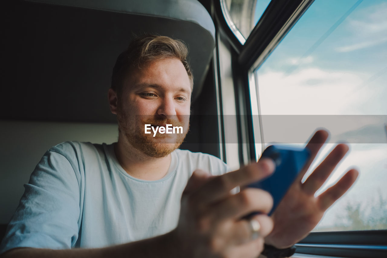 A man using a smartphone while traveling by railway train