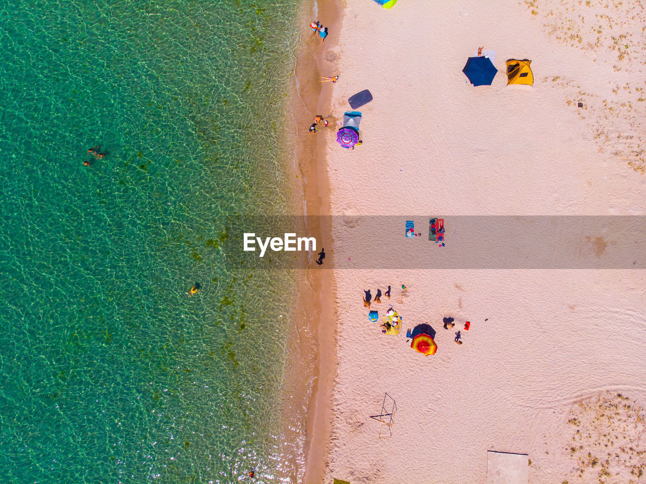 Aerial view of a sandy beach with people resting and parasols. view from above