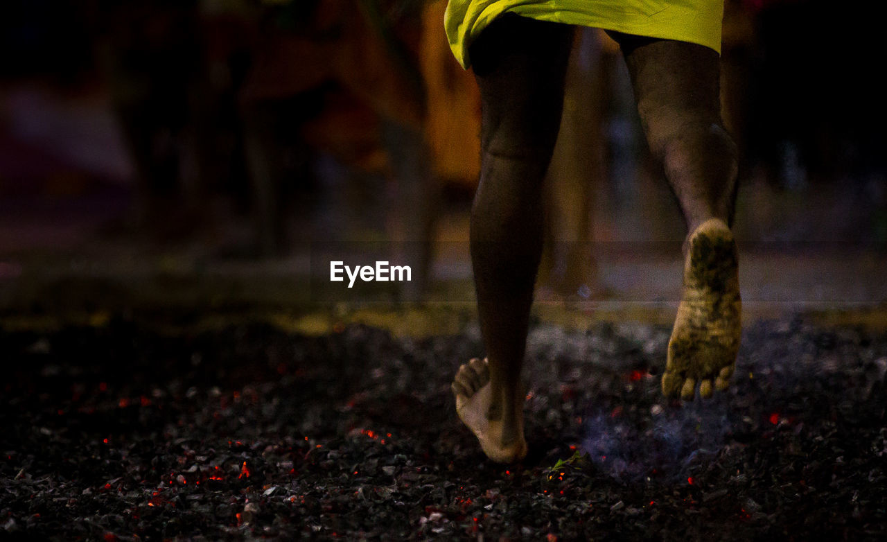 Low section of man running barefoot on hot coals